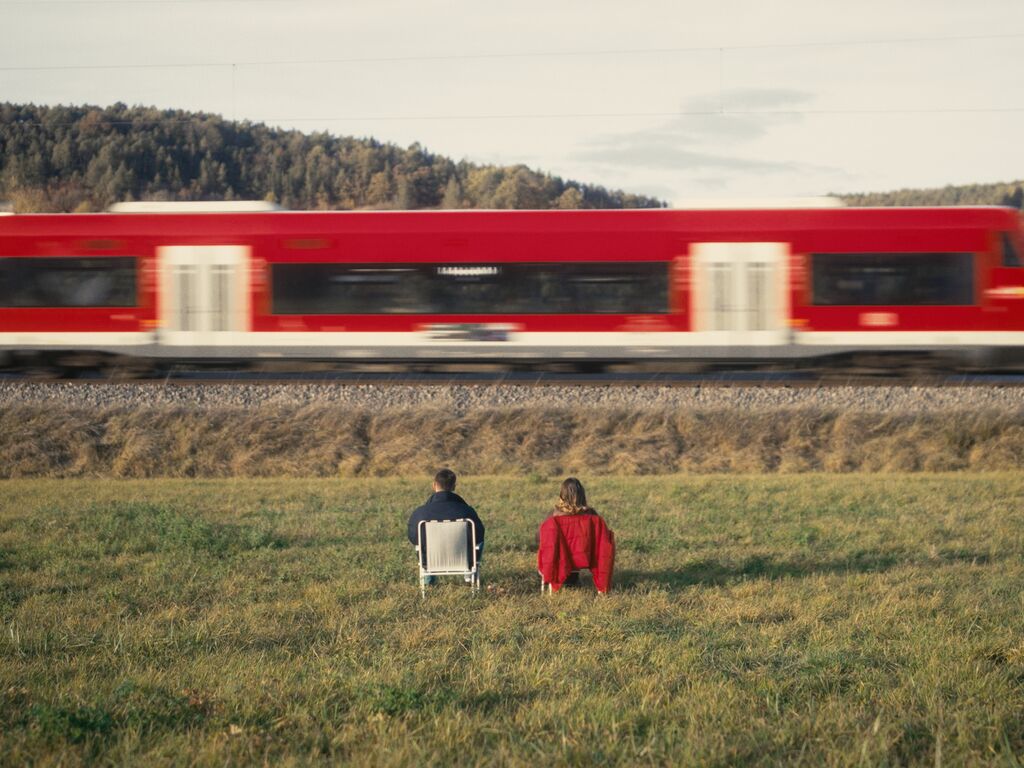 Red train passing the characters in Mut zum Zug